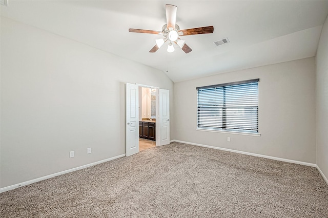 unfurnished bedroom featuring connected bathroom, ceiling fan, light carpet, and vaulted ceiling