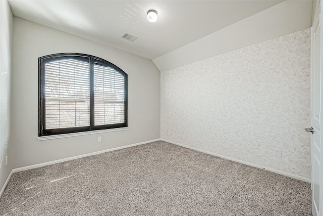 carpeted empty room featuring vaulted ceiling