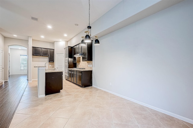 kitchen with pendant lighting, light tile patterned flooring, sink, and a kitchen island with sink