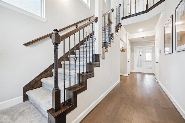 stairs featuring hardwood / wood-style floors, ornamental molding, a wealth of natural light, and french doors