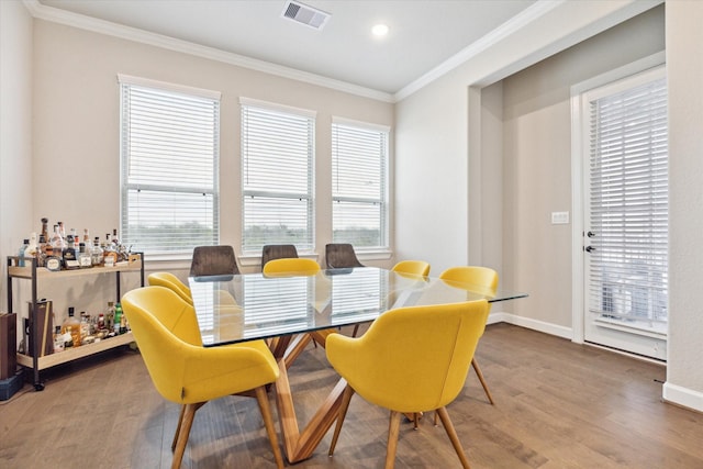 dining space featuring ornamental molding, wood-type flooring, and plenty of natural light