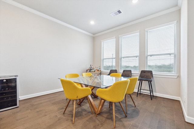 dining area with wine cooler, dark wood-type flooring, ornamental molding, and a healthy amount of sunlight