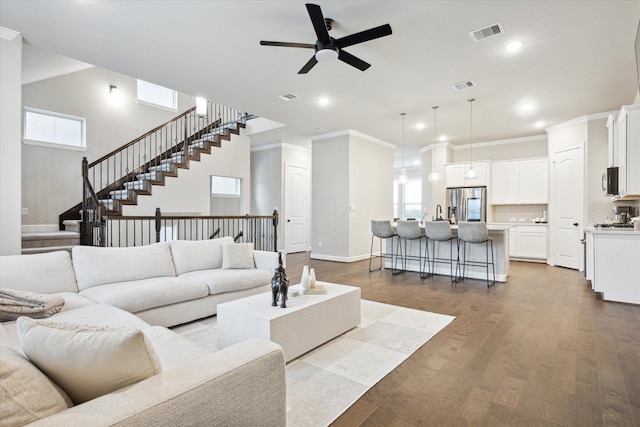 living room featuring wood-type flooring, ornamental molding, ceiling fan, and plenty of natural light