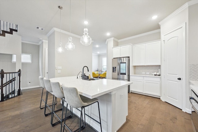 kitchen featuring an island with sink, sink, white cabinets, and decorative light fixtures