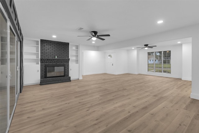 unfurnished living room featuring ceiling fan, a fireplace, and light hardwood / wood-style floors