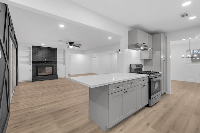 kitchen featuring a fireplace, built in shelves, gray cabinets, and stainless steel range with gas stovetop