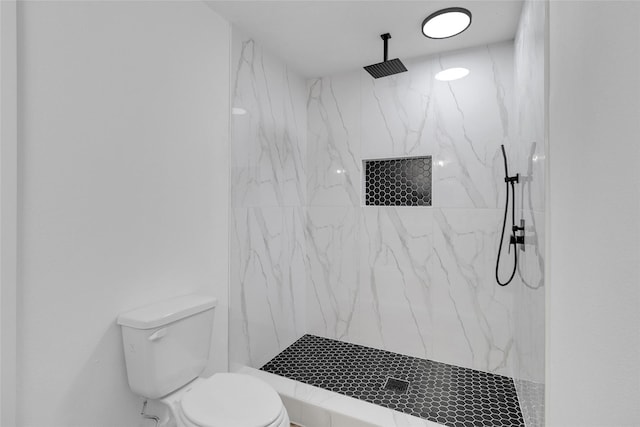 bathroom featuring a tile shower and toilet