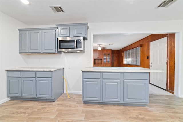 kitchen featuring ceiling fan, wood walls, kitchen peninsula, and light hardwood / wood-style flooring