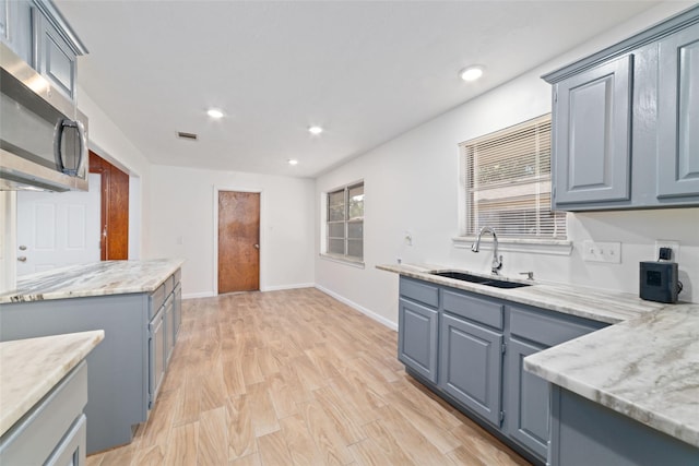 kitchen featuring light stone countertops, light hardwood / wood-style flooring, and sink