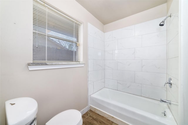 bathroom with wood-type flooring, tiled shower / bath combo, and toilet