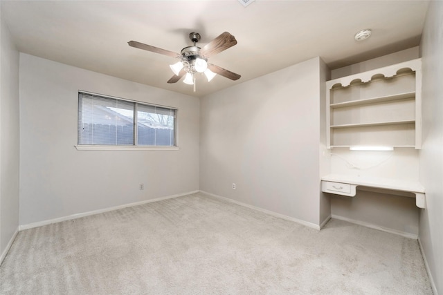 interior space with ceiling fan, light colored carpet, and built in desk