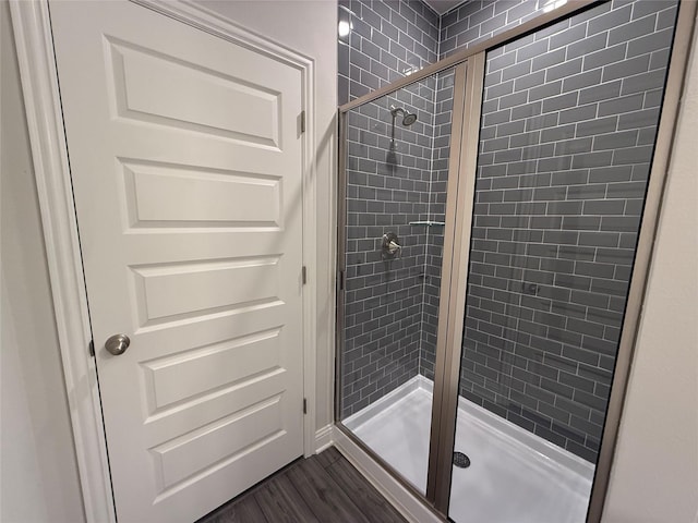 bathroom featuring a shower with shower door and wood-type flooring