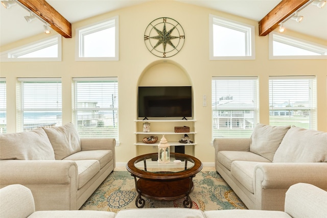 living area with baseboards, lofted ceiling with beams, and track lighting