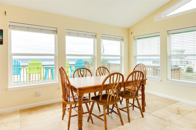 dining room with a wealth of natural light, lofted ceiling, and baseboards