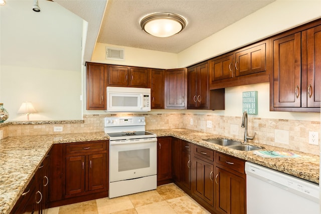 kitchen featuring light stone counters, tasteful backsplash, visible vents, a sink, and white appliances