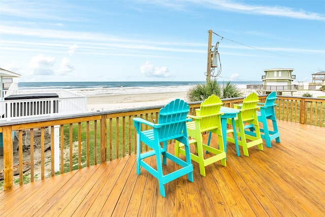 wooden terrace featuring a water view and a beach view