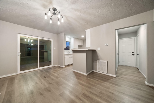 unfurnished living room with a textured ceiling and light wood-type flooring