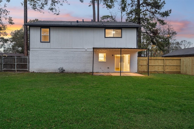 back house at dusk featuring a yard and a patio