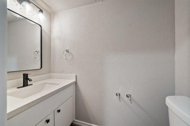 bathroom with toilet, vanity, and a textured ceiling