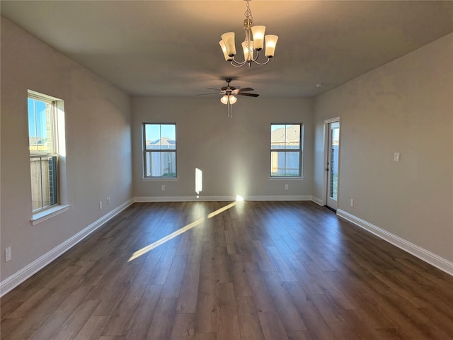 empty room featuring ceiling fan with notable chandelier and dark wood-type flooring