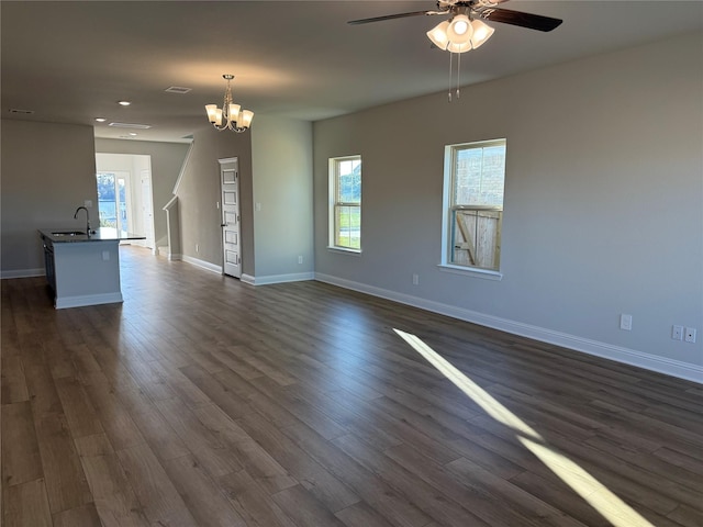 unfurnished living room featuring dark hardwood / wood-style flooring, ceiling fan with notable chandelier, and sink