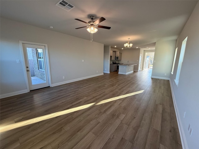 unfurnished living room with ceiling fan with notable chandelier and dark hardwood / wood-style flooring