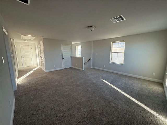 unfurnished room with a healthy amount of sunlight and dark colored carpet