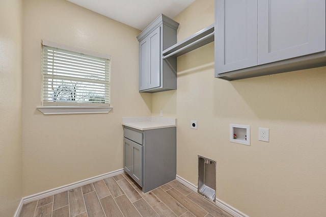 washroom featuring hookup for an electric dryer, washer hookup, light hardwood / wood-style flooring, and cabinets