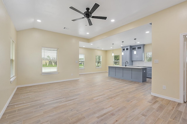 unfurnished living room with ceiling fan, lofted ceiling, and sink