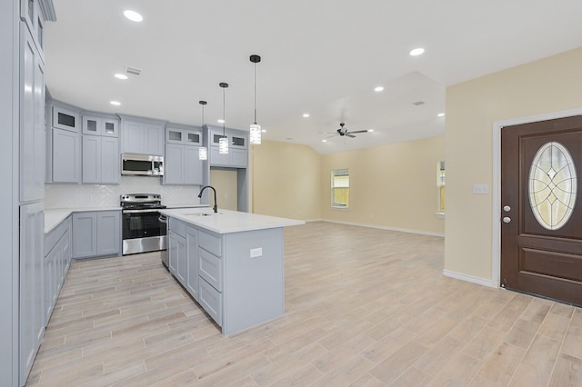 kitchen featuring pendant lighting, a center island with sink, sink, ceiling fan, and appliances with stainless steel finishes