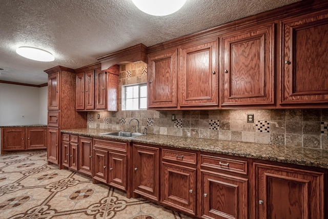 kitchen featuring a textured ceiling, stone countertops, ornamental molding, and sink