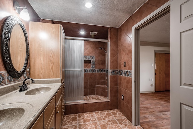 bathroom featuring a tile shower, vanity, and a textured ceiling