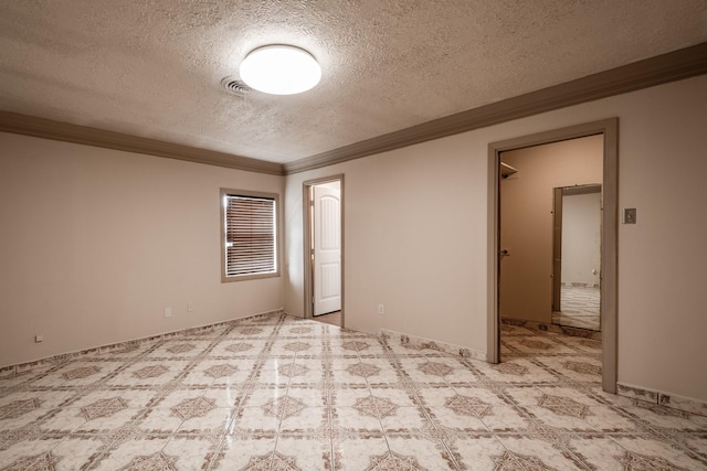 unfurnished bedroom featuring crown molding, light colored carpet, a textured ceiling, a walk in closet, and a closet