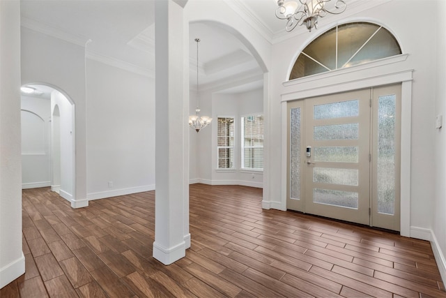 foyer entrance featuring ornamental molding, dark hardwood / wood-style floors, a high ceiling, and a notable chandelier