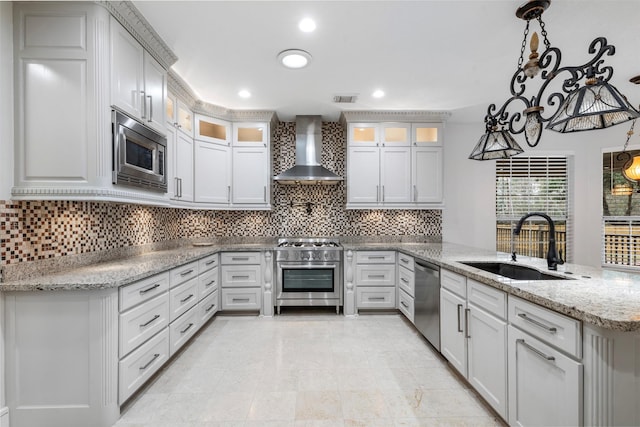 kitchen featuring appliances with stainless steel finishes, decorative light fixtures, wall chimney range hood, and kitchen peninsula