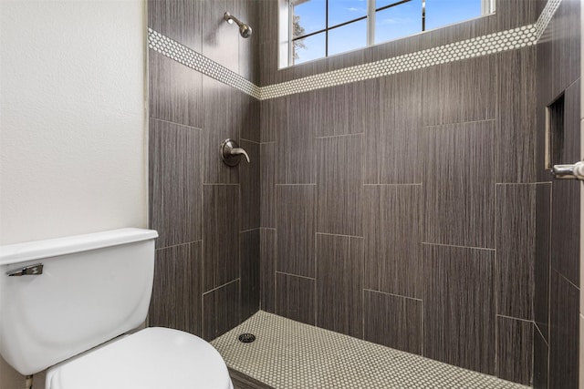 bathroom featuring a tile shower and toilet