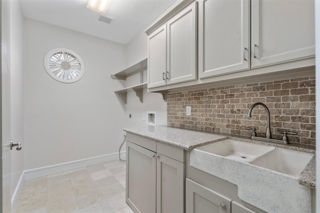 kitchen featuring light stone countertops, sink, and decorative backsplash