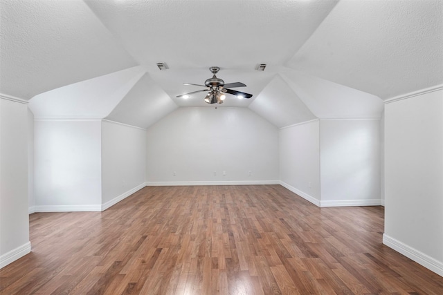 additional living space with lofted ceiling, a textured ceiling, wood-type flooring, and ceiling fan