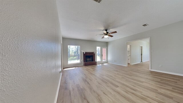 unfurnished living room with a fireplace, light hardwood / wood-style floors, and ceiling fan