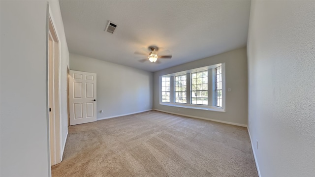 empty room with ceiling fan and light carpet