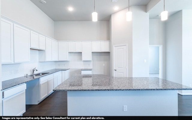 kitchen with white cabinetry, sink, hanging light fixtures, and stone countertops