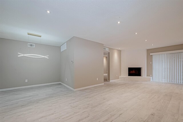 unfurnished living room featuring a textured ceiling and light hardwood / wood-style flooring