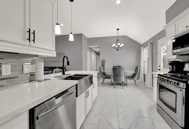 kitchen with pendant lighting, lofted ceiling, backsplash, white cabinetry, and stainless steel appliances