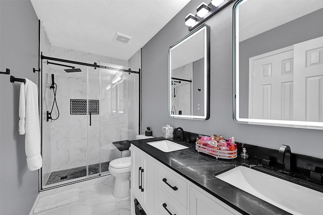 bathroom with vanity, toilet, a shower with shower door, and a textured ceiling