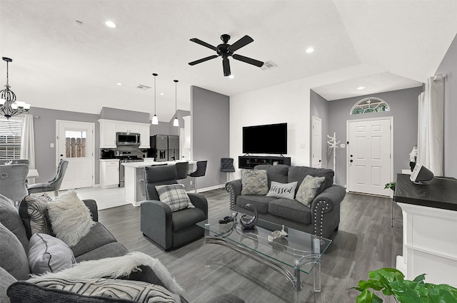 living room featuring ceiling fan with notable chandelier, dark hardwood / wood-style floors, and lofted ceiling