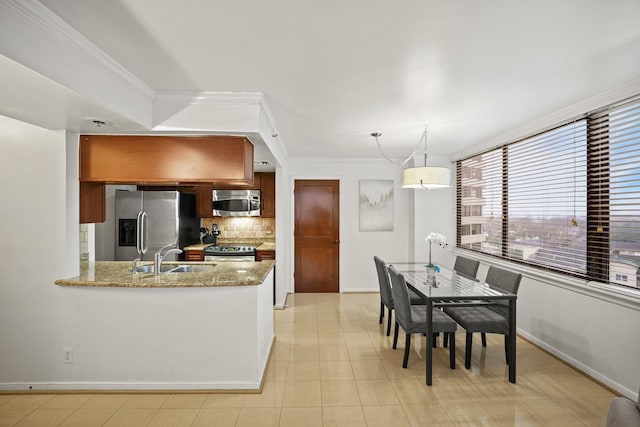 kitchen featuring backsplash, sink, ornamental molding, appliances with stainless steel finishes, and decorative light fixtures