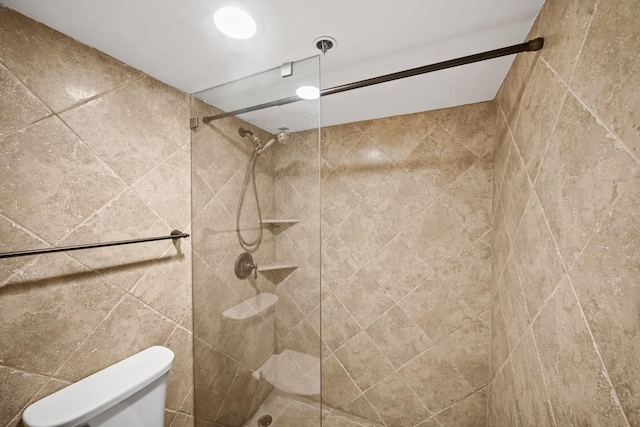 bathroom featuring tiled shower and toilet