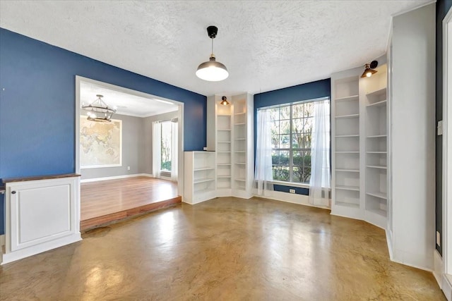 unfurnished living room with built in features, concrete floors, a textured ceiling, and a notable chandelier