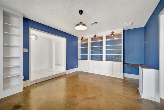 spare room featuring built in shelves and a textured ceiling