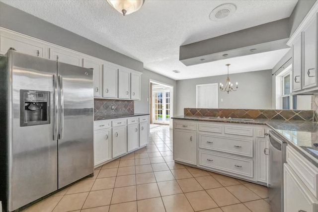 kitchen featuring appliances with stainless steel finishes, a textured ceiling, tasteful backsplash, and white cabinetry